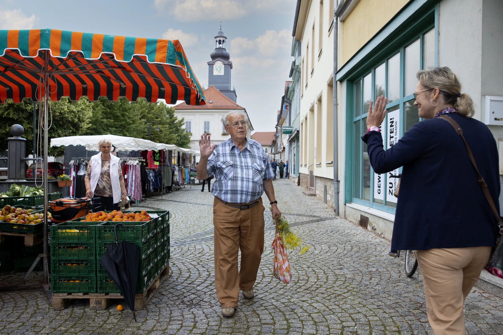 Ein Mann und eine Frau grüßen sich auf dem Marktplatz.